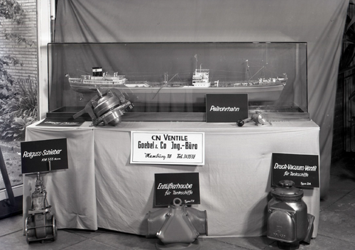 A historical picture of a Table with a miniature ship and multiple small ship parts from CN Ventile Goebel & Co.