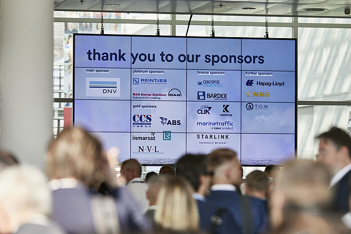 Eingangsbereich auf der SMM, es ist Menschenmenge zu sehen sowie eine digitale Anzeige mit Sponsoren.