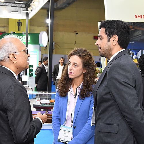 Drei Aussteller unterhalten sich auf einer Messe. 